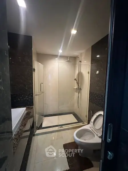 Luxurious modern bathroom with glass shower and elegant tile design.