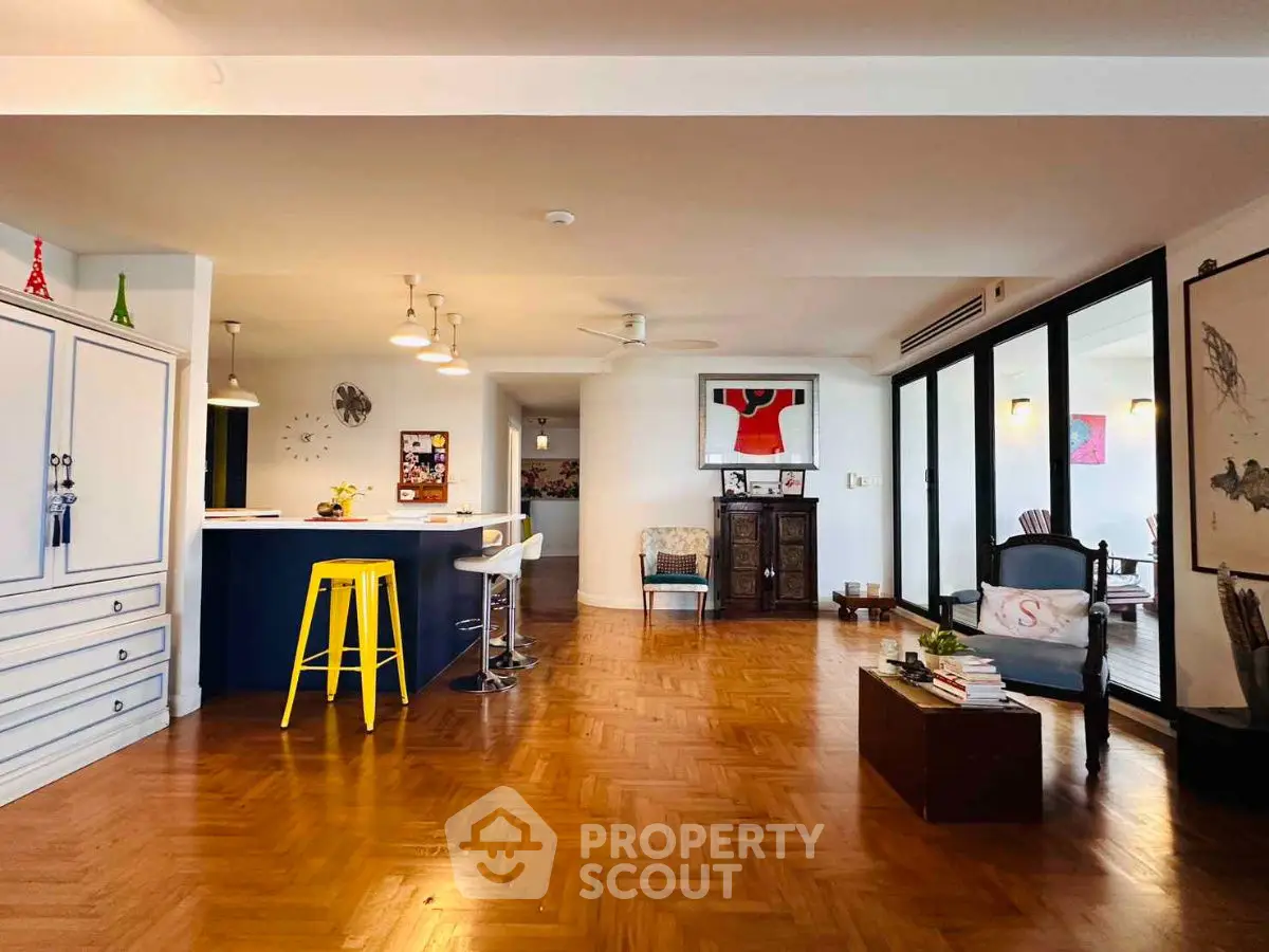 Spacious open-layout living room with stylish decor and wooden flooring.