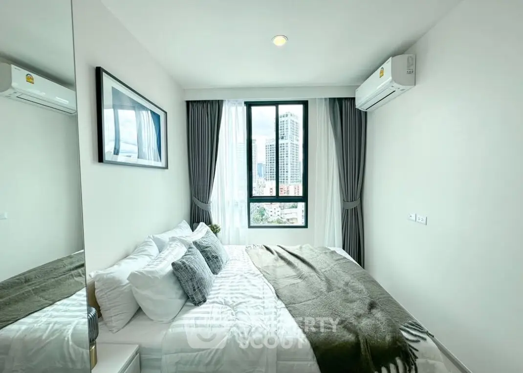 Modern bedroom with city view, featuring cozy bedding and air conditioning.