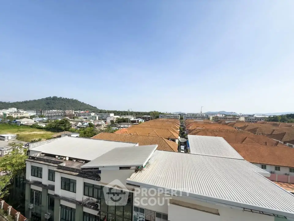 Scenic rooftop view showcasing residential buildings and lush greenery in the background.