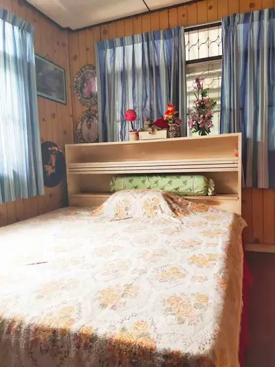 Cozy bedroom with vintage decor and wooden paneling, featuring a large bed and floral accents.