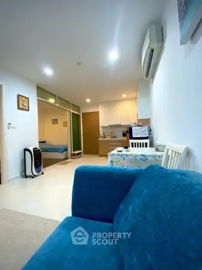 Modern open-plan living room with blue sofa and compact kitchen area