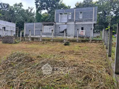 Unfinished concrete building on a spacious plot surrounded by greenery, ideal for development.