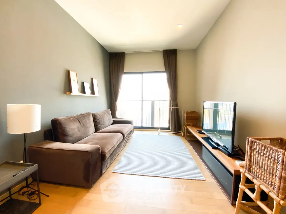 Modern living room with cozy brown sofa, large window, and stylish decor in a bright apartment.