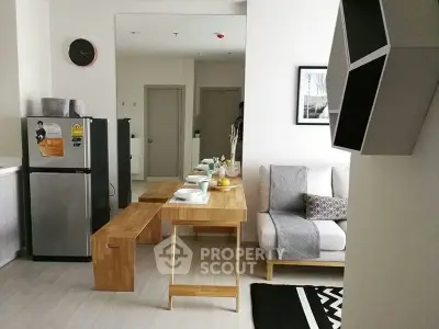 Modern living room with sleek furniture and compact kitchen area in a stylish apartment.