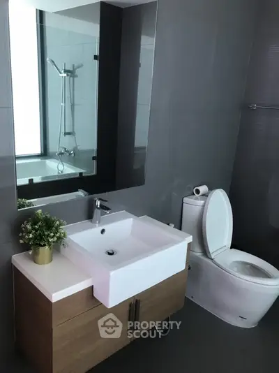 Modern bathroom with sleek fixtures and a large mirror, featuring a stylish vanity and toilet.
