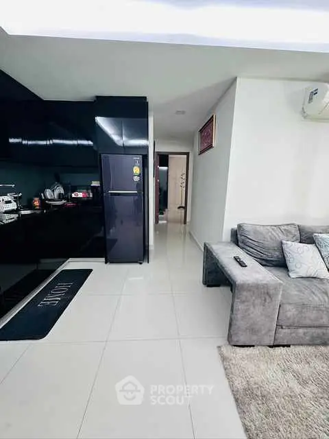 Modern open-plan living room with sleek kitchen and cozy gray sofa.