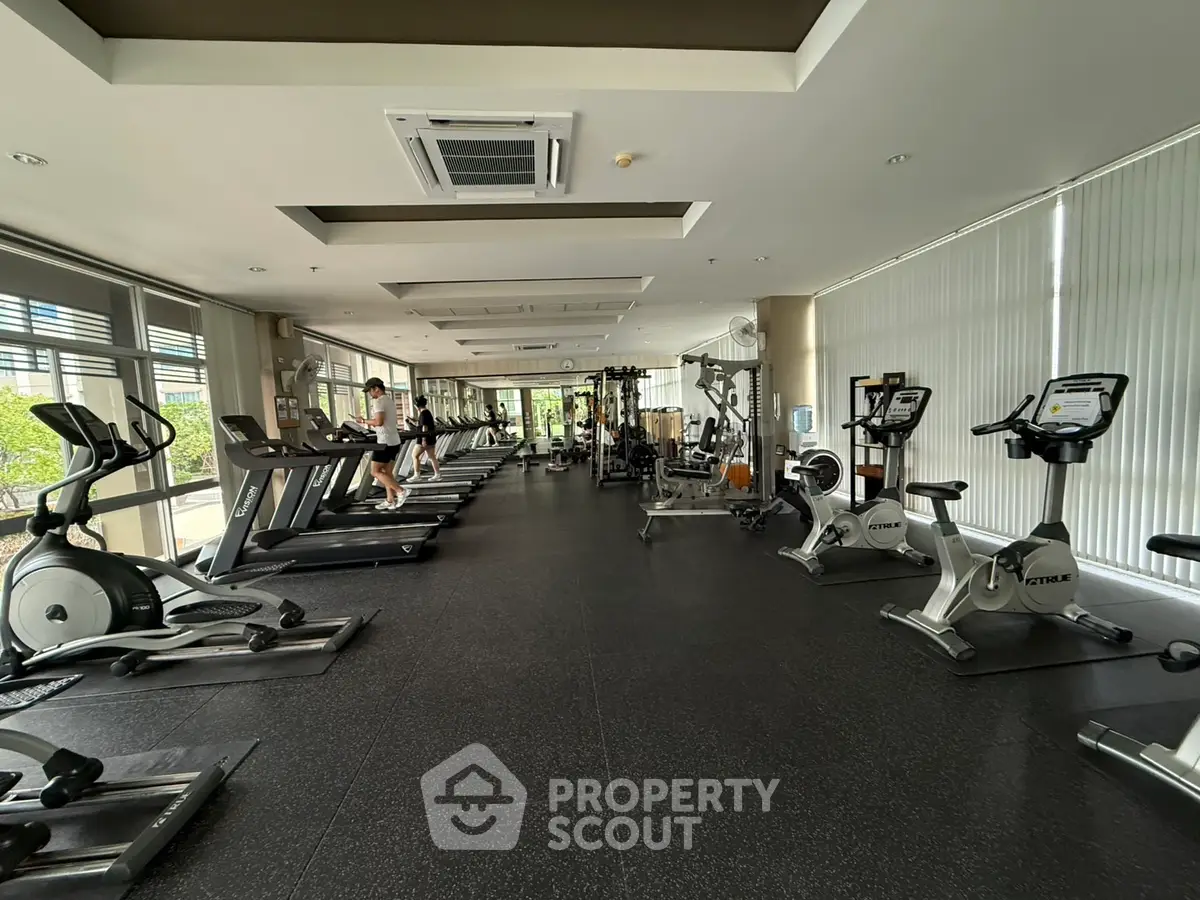Spacious modern gym with state-of-the-art equipment and large windows for natural light.