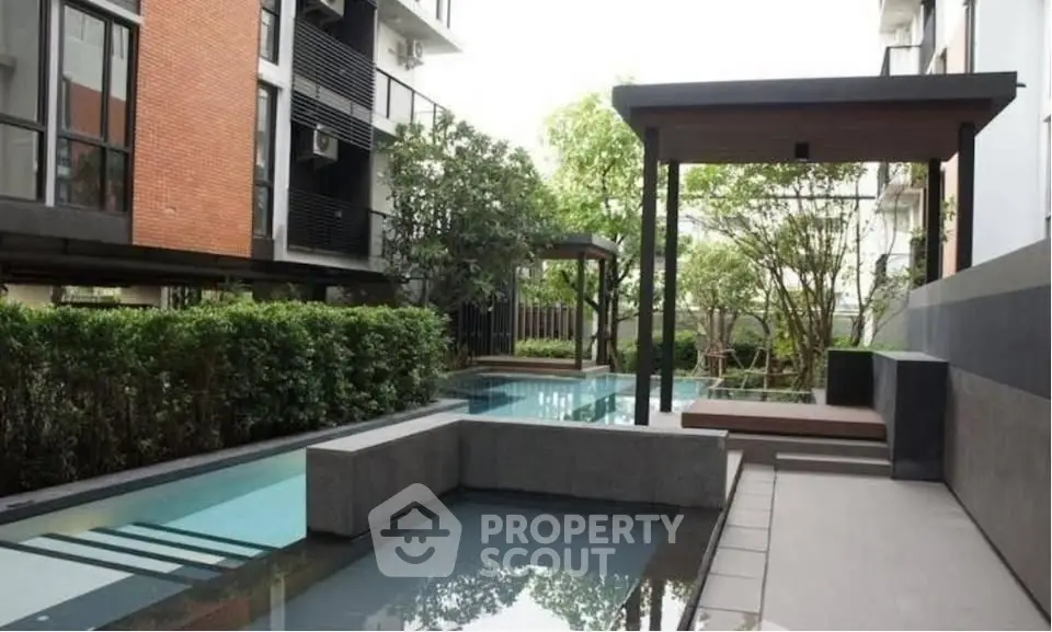 Modern apartment complex with serene pool and lush greenery