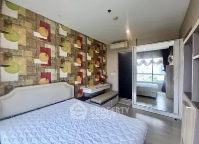 Modern bedroom with stylish wallpaper and mirrored wardrobe in a cozy apartment.