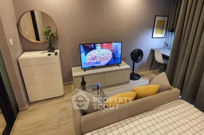 Modern living room with stylish decor, TV, and cozy workspace in a contemporary apartment.
