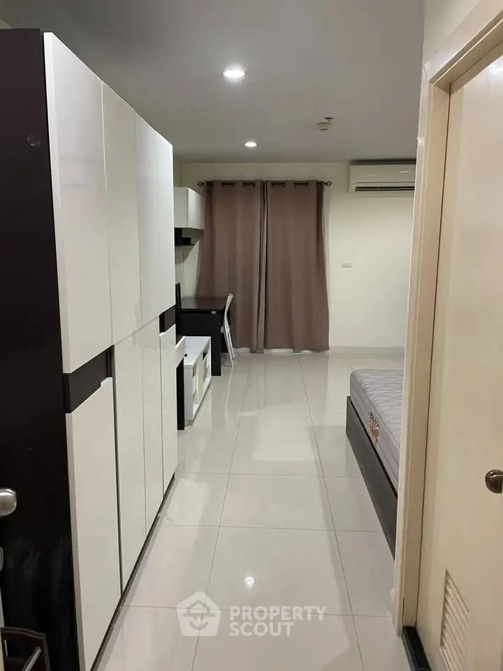 Modern studio apartment with sleek furniture and neutral decor, featuring a comfortable bed and workspace.