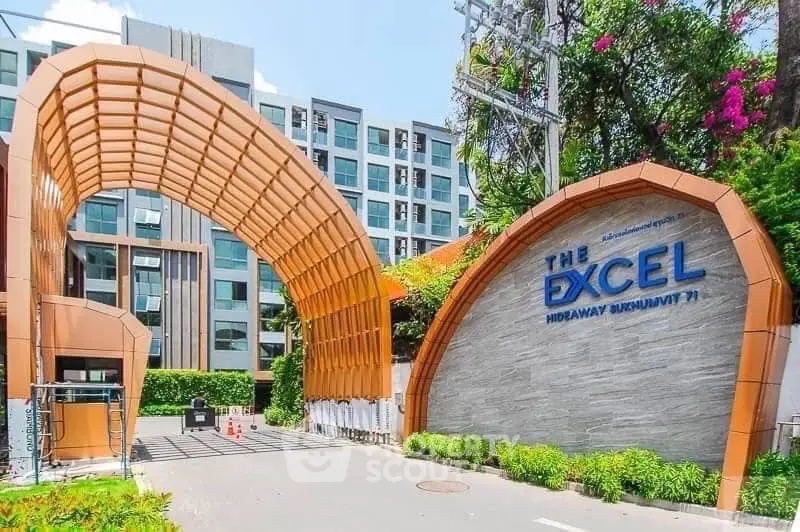 Modern apartment complex entrance with unique architectural design and lush greenery.