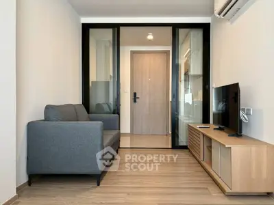 Modern living room with sleek furniture and wooden flooring, featuring a cozy sofa and a flat-screen TV.