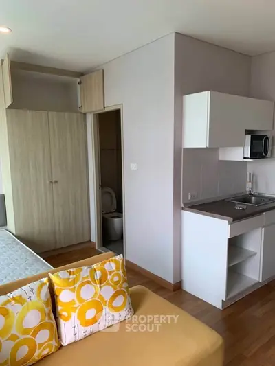 Modern studio apartment with compact kitchen and cozy living area, featuring bright decor and efficient use of space.
