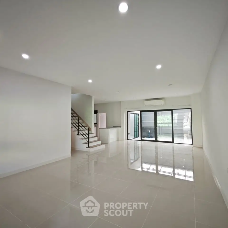 Spacious modern living room with large windows and sleek staircase