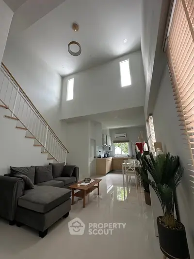 Modern open-plan living room with high ceiling and natural light