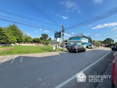 Charming suburban street view with residential building and lush greenery.