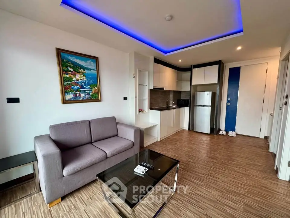 Modern living room with open kitchen, stylish lighting, and cozy seating in a contemporary apartment.