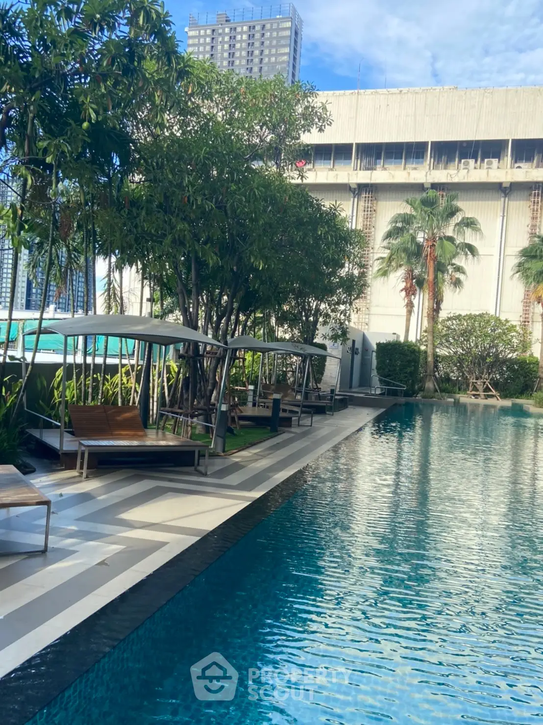 Luxurious outdoor pool area with lush greenery and modern lounging spaces in a high-rise building setting.