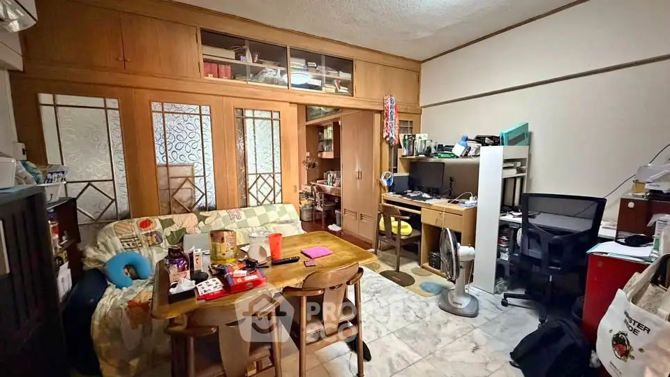 Cozy living room with wooden accents and marble flooring, featuring a small dining area and workspace.