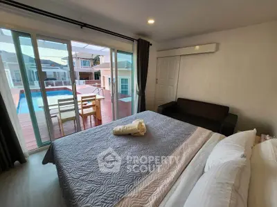 Spacious bedroom with pool view and cozy seating area, perfect for relaxation.
