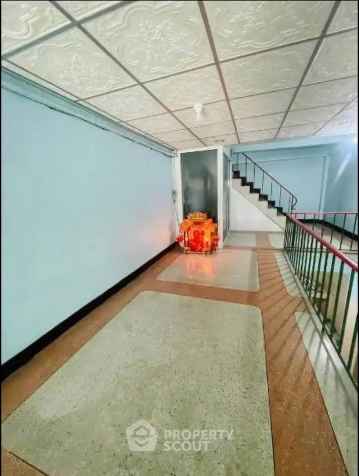 Spacious building corridor with decorative ceiling and staircase