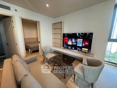 Modern living room with sleek furniture and large TV, adjacent to a cozy bedroom.