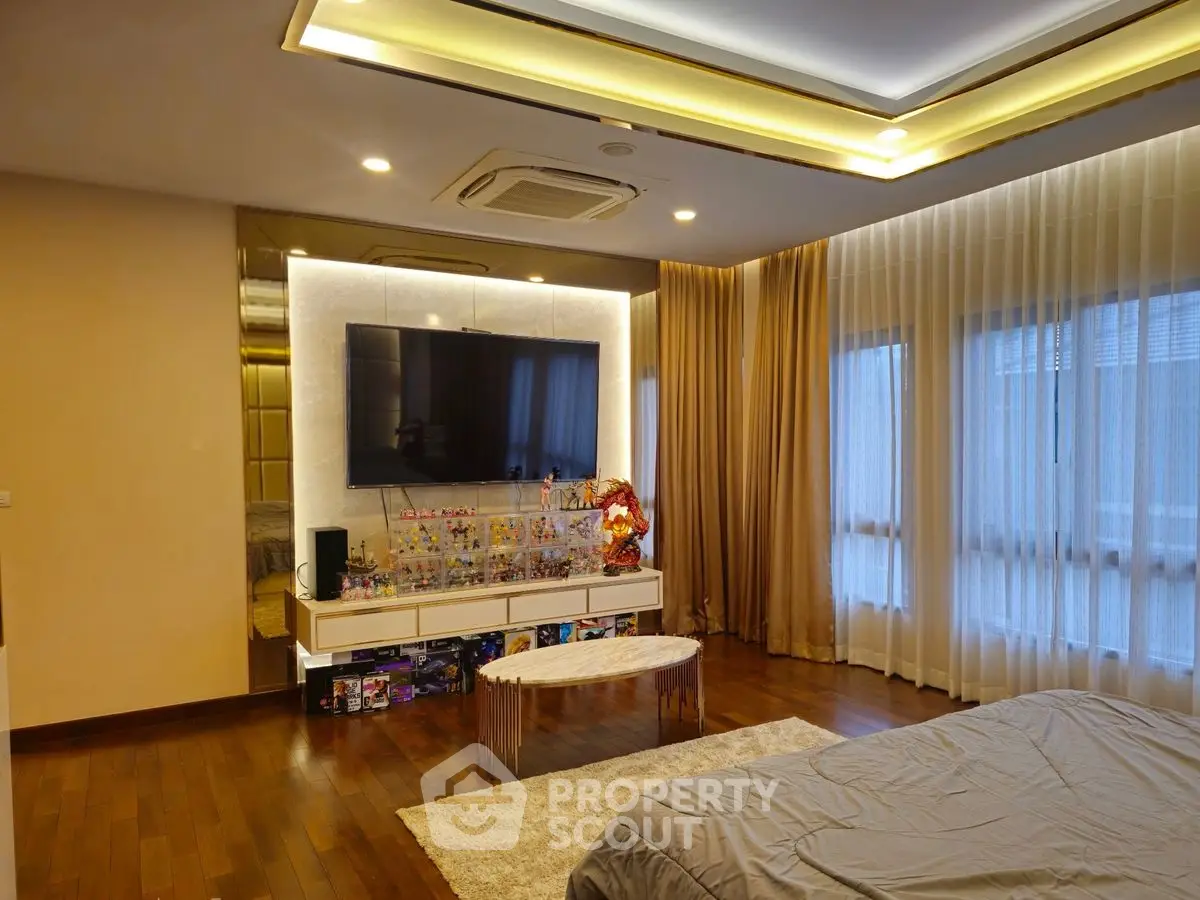 Luxurious bedroom with modern decor and large TV, featuring elegant lighting and hardwood floors.