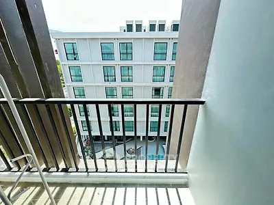 Modern apartment building view from balcony with sleek design and pool area.