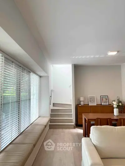 Modern living room with natural light, cozy seating, and elegant dining area, perfect for family gatherings.