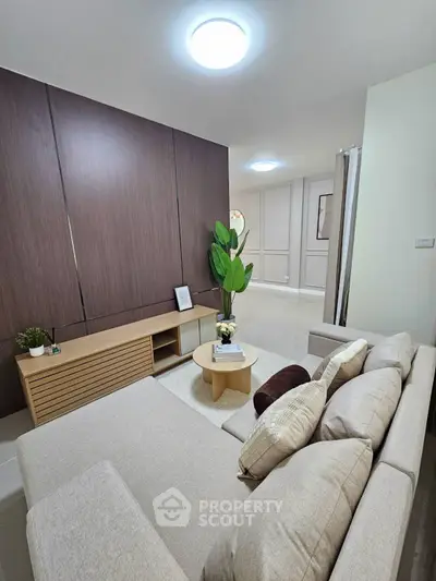 Modern living room with cozy beige sofa, stylish wooden paneling, and elegant decor for a welcoming ambiance.