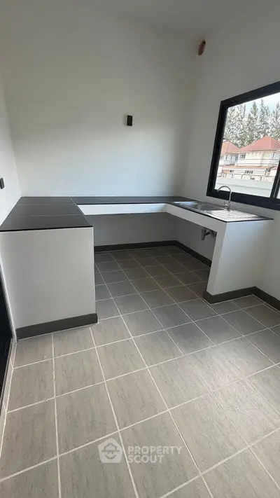 Modern kitchen with sleek countertops and large window offering natural light.