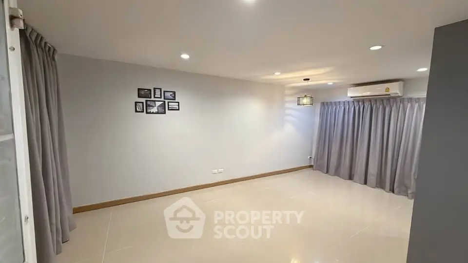 Spacious modern living room with sleek tile flooring and elegant lighting.