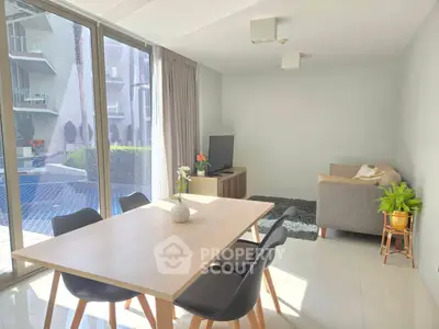 Modern living room with pool view, stylish furniture, and abundant natural light.