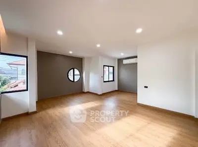 Spacious modern living room with wooden flooring and ample natural light.