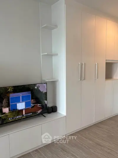 Modern living room with sleek white cabinetry and built-in TV unit, showcasing minimalist design.