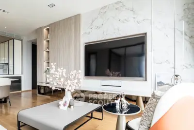 Luxurious modern living room with elegant decor and large flat-screen TV, featuring marble accent wall and stylish furniture.