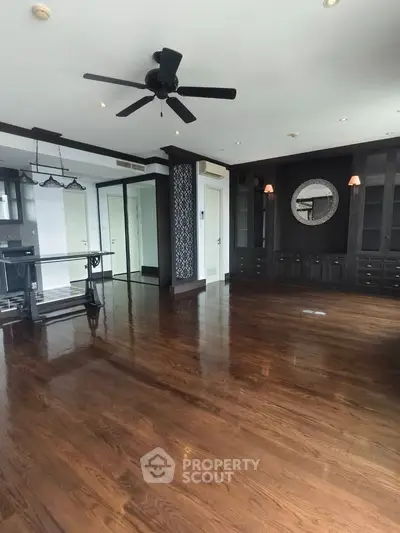 Spacious living room with elegant dark wood flooring and ceiling fan