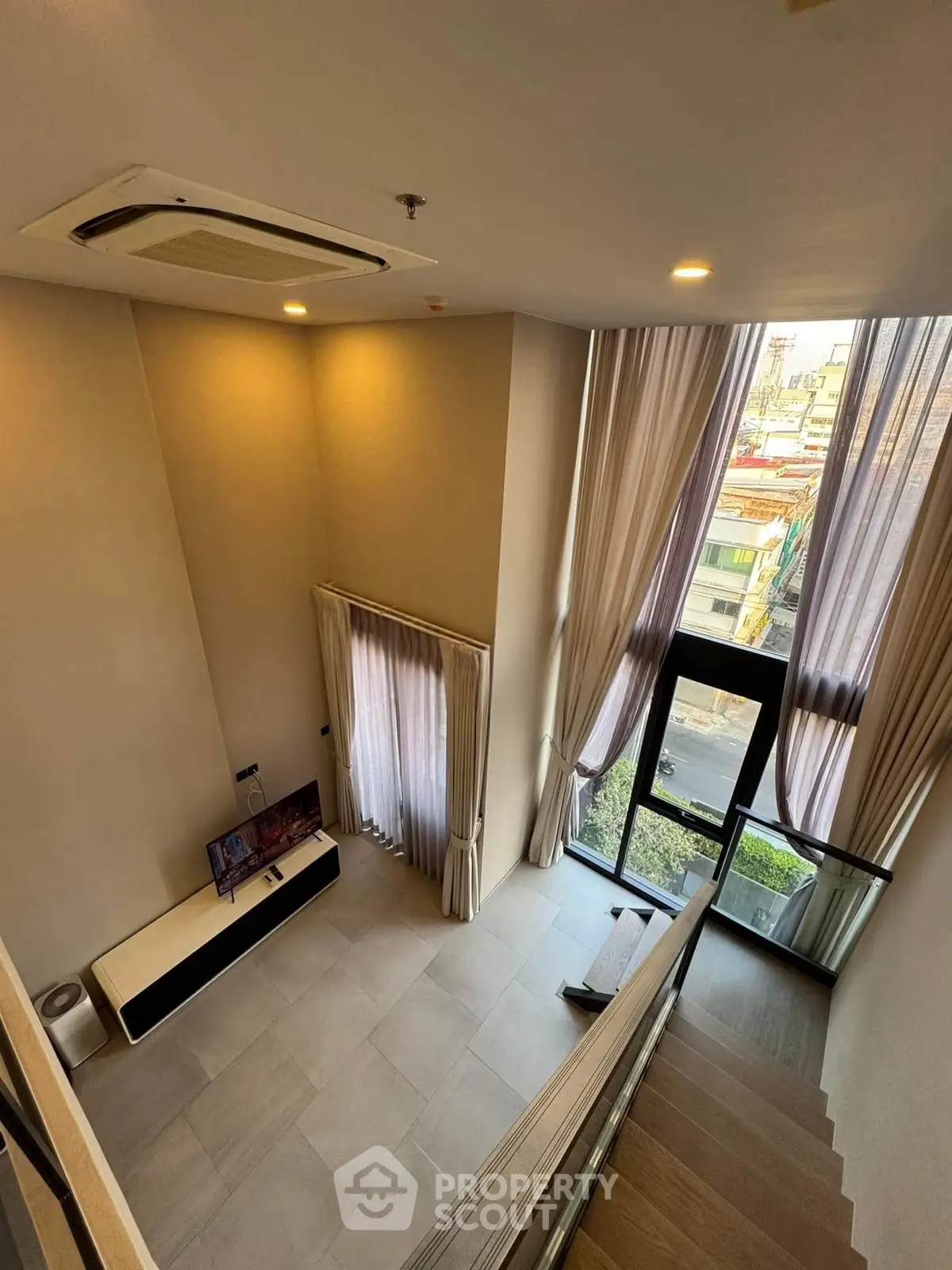 Stunning high-ceiling living room with large windows and city view, perfect for modern urban living.