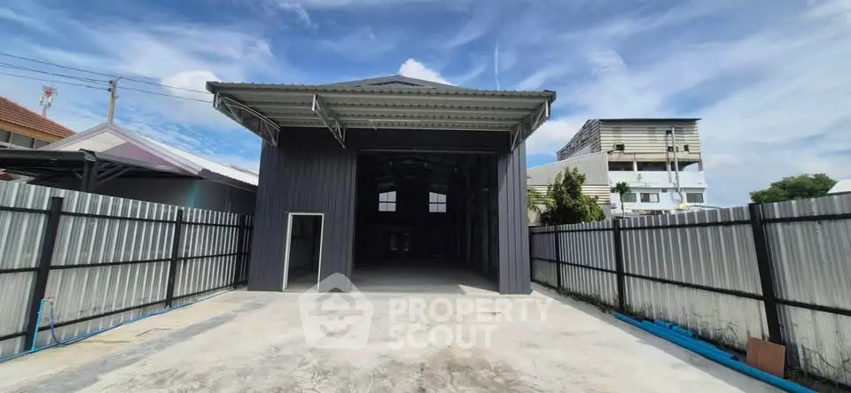 Spacious industrial warehouse with high ceiling and secure fencing, ideal for storage or business operations.