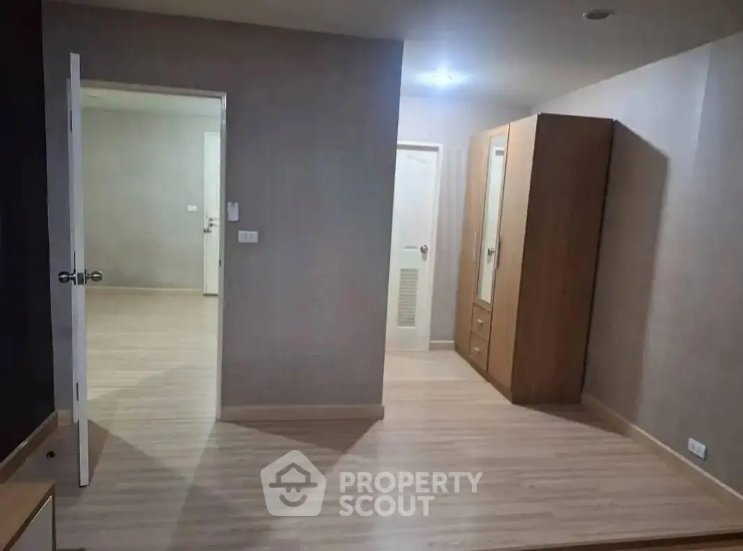 Spacious bedroom with wooden flooring and wardrobe in modern apartment.