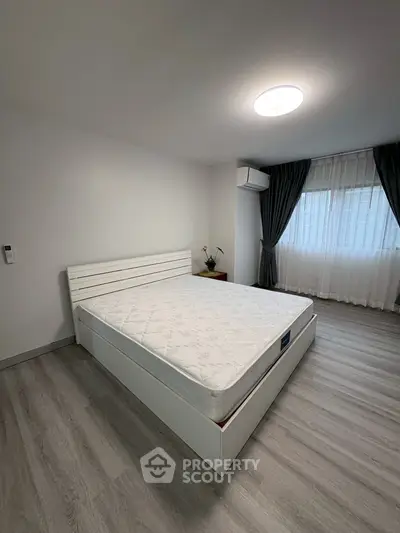 Spacious bedroom with modern decor and large window for natural light