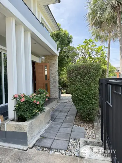 Charming modern house entrance with lush greenery and stone pathway