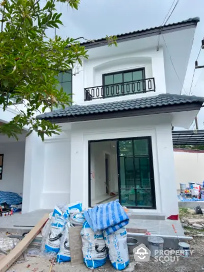 Modern two-story house under construction with white exterior and black roof tiles