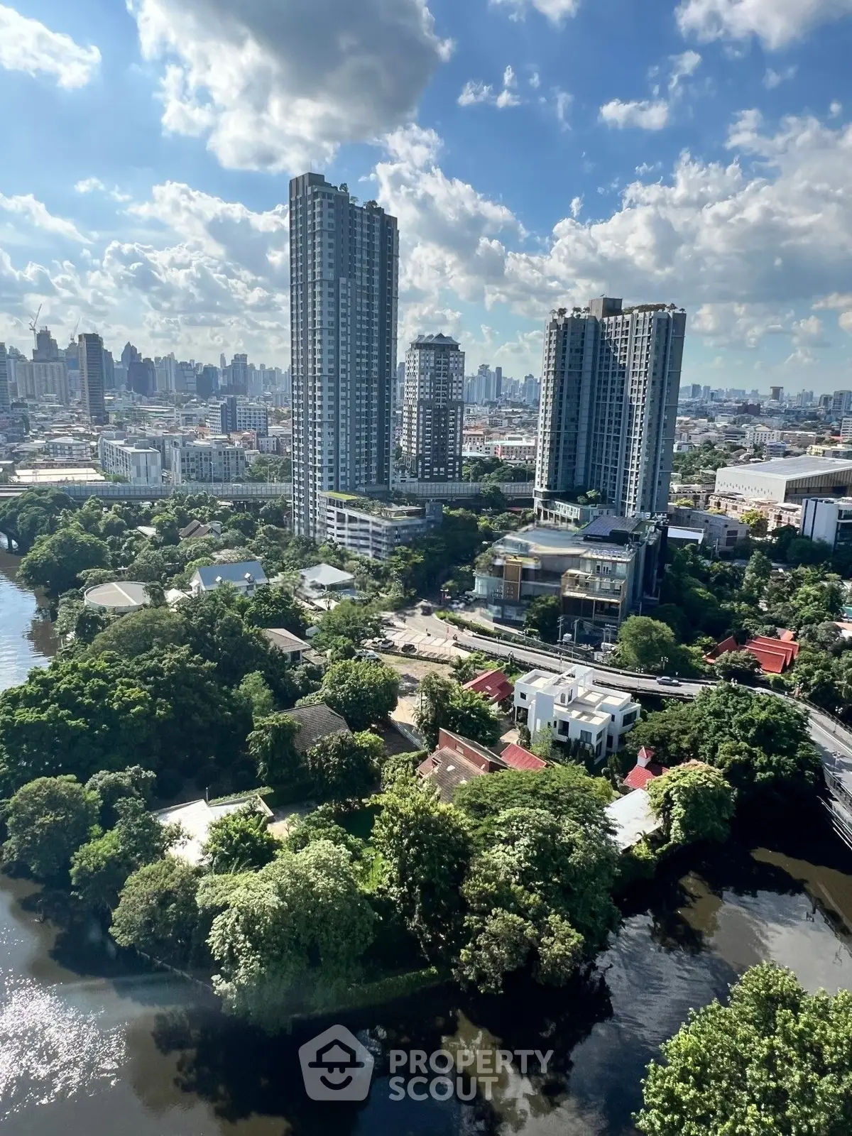 Stunning cityscape view with high-rise buildings and lush greenery by the river, perfect for urban living.