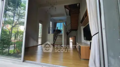 Spacious modern living room with high ceilings and large windows overlooking greenery.