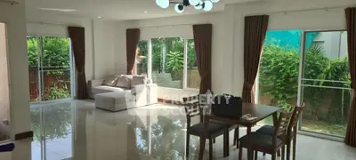 Spacious living room with large windows and garden view, featuring modern furniture and elegant decor.