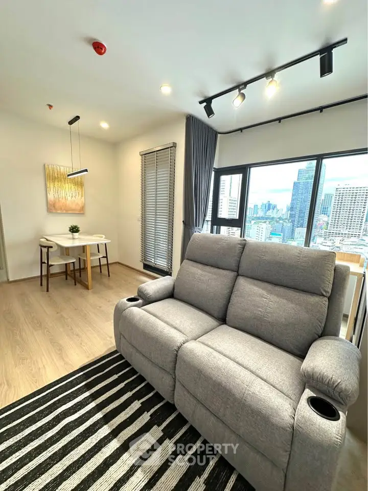 Modern living room with city view, featuring a cozy gray sofa and stylish dining area.