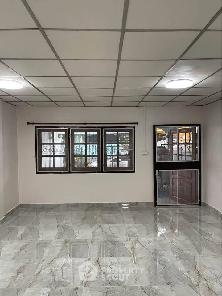 Spacious living room with modern tiled flooring and large windows for natural light.